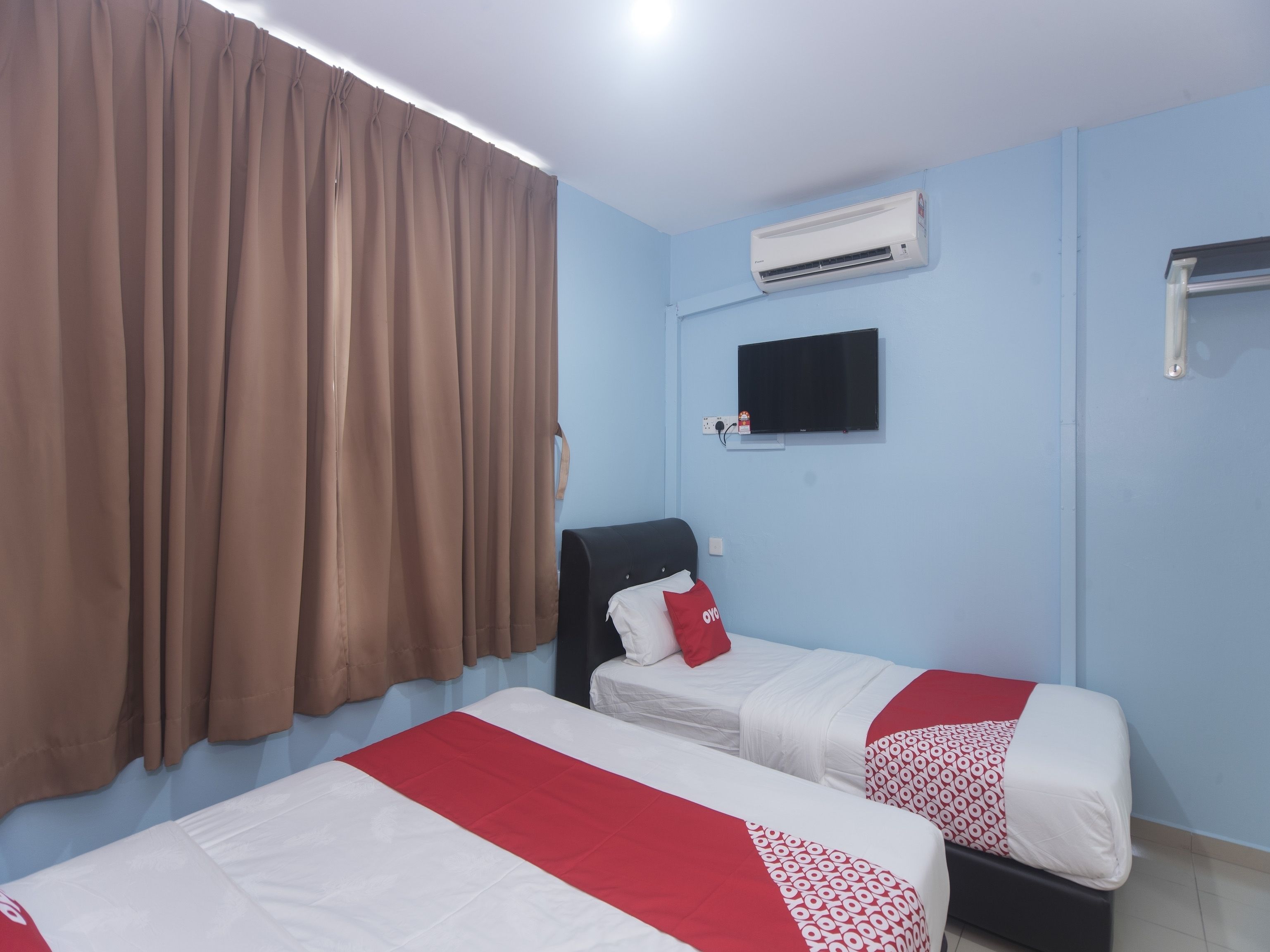 Habitación de hotel con dos camas, televisión, aire acondicionado y una ventana con cortinas.
