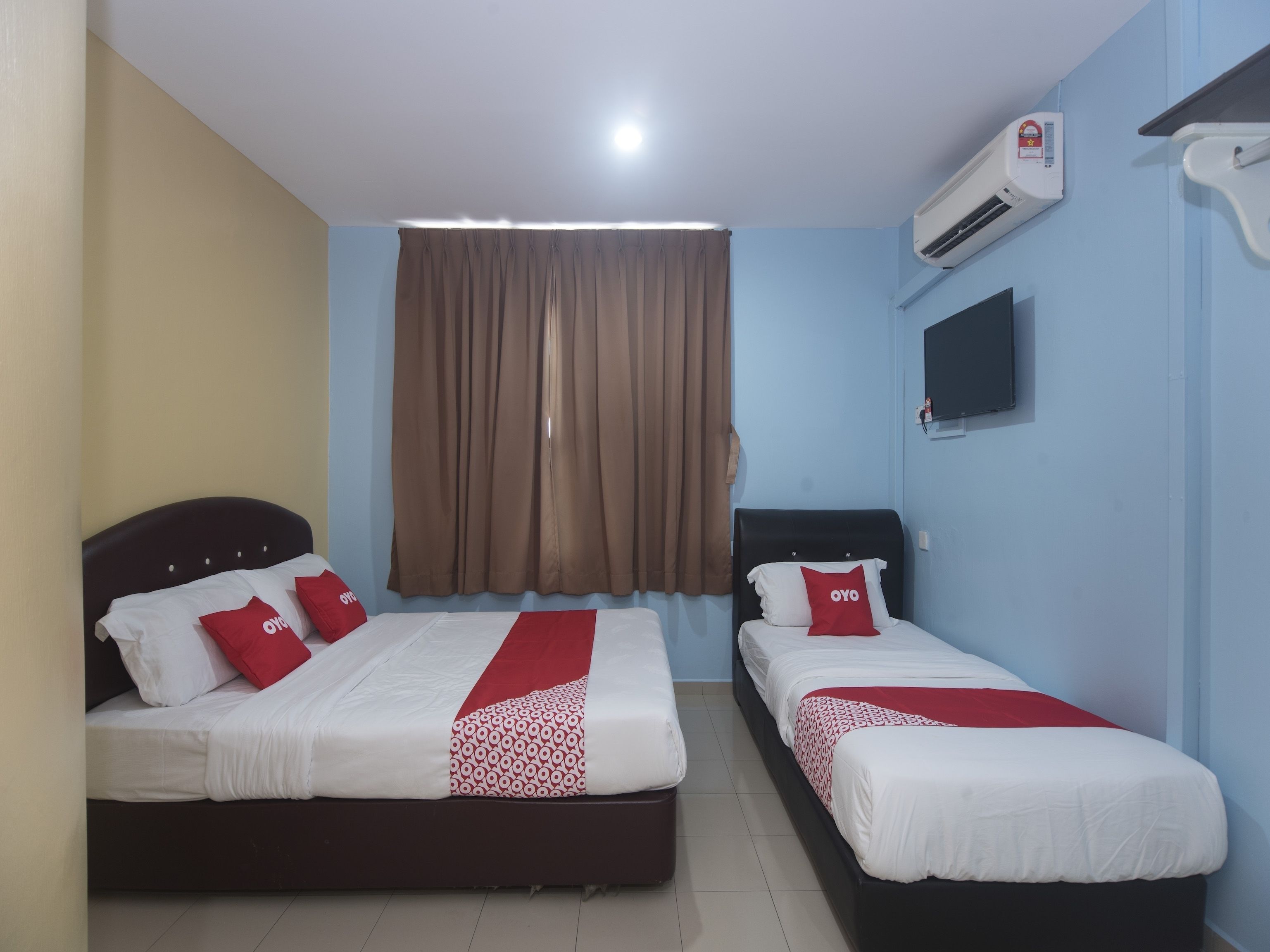 Habitación de hotel con dos camas, televisión, aire acondicionado y ventana con cortinas.