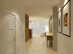 A modern hotel lobby with a reception desk, a seating area, and framed artwork on the walls. - Merlin Hotel (Maumere)