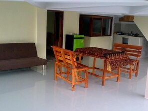 A dining area with a table and chairs, a sofa, and a kitchen in the background. - Hinwong Apartments Dive & Snorkel Resort (Koh Tao)