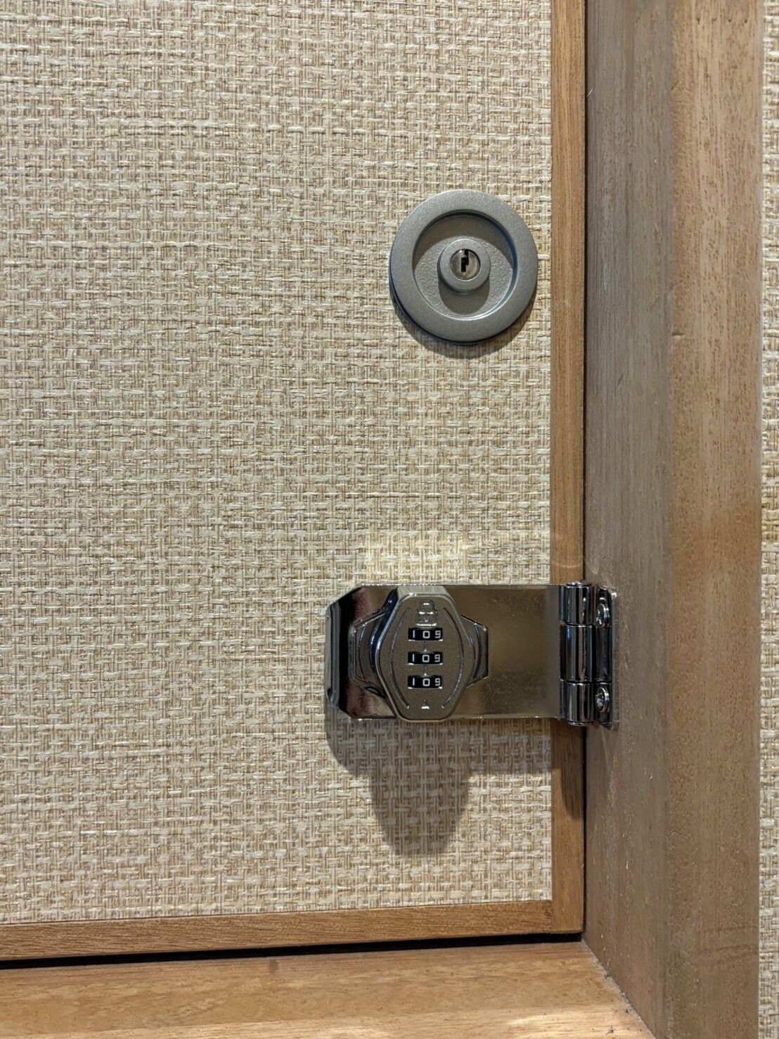 Una puerta con un panel de tela texturizada y un mecanismo de cierre metálico.