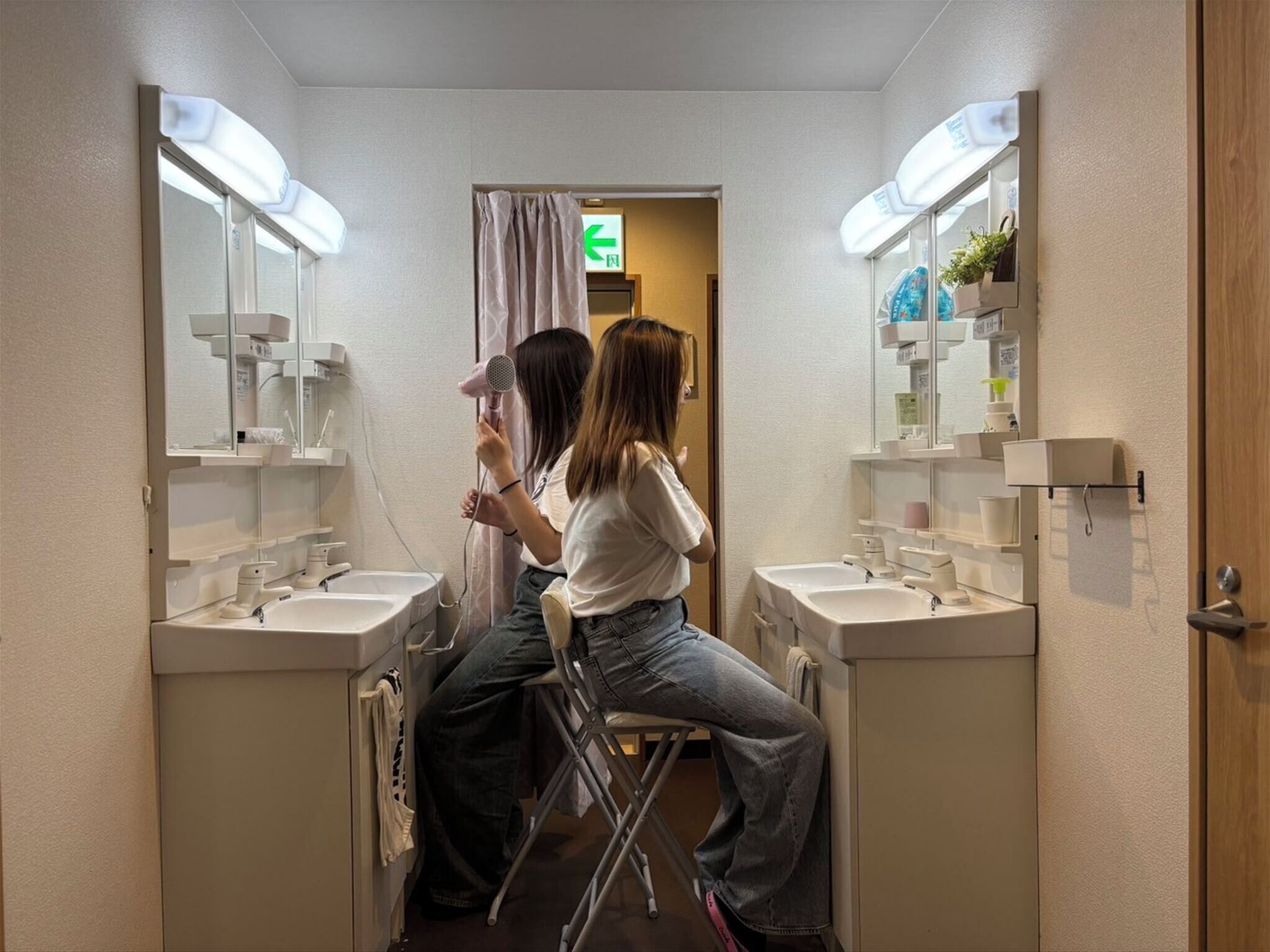 A narrow bathroom with two sinks, a mirror, and a shower area.