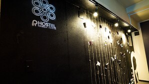 A wall with a hostel logo and name, a door with a number, and a wall with hanging items. - R Hostel Namba South (Osaka)