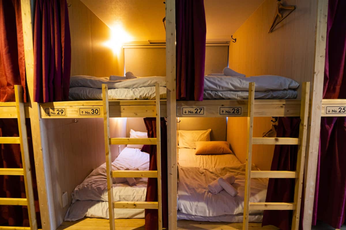 Bunk beds in a room with wooden walls and purple curtains.