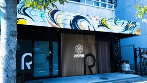 A hostel with a modern design, featuring a wooden facade and a colorful mural on the exterior wall. - R Hostel Namba South (Osaka)