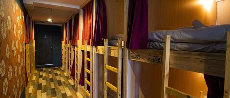 A corridor with bunk beds, each with a number label, and a checkered floor.