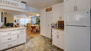 A kitchen with white cabinets, a large refrigerator, and a dining area with a table and chairs. - Gorgeous Downtown Delray Beach Cottage (Delray Beach)
