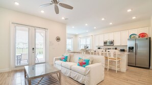 A modern kitchen with white cabinets, stainless steel appliances, and a dining area with a white table and chairs.