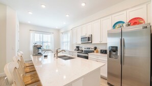 A modern kitchen with white cabinetry, stainless steel appliances, and a central island with seating.