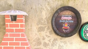 Ein Backofen aus Ziegelsteinen mit Schornstein, ein kleiner Tisch mit einer runden Holzplatte und eine an der Wand befestigte Plakette.