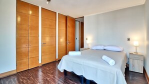 Ein Schlafzimmer mit einem großen Bett, einem Holzschrank, Nachttischen und einem Nachtkästchen.