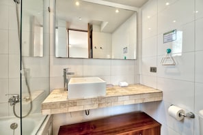 A modern bathroom with a large mirror, a white sink, and a shower area. - Vespucio Art (Santiago)