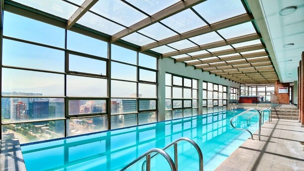 Ein Innenpool mit Blick auf die Stadt, großen Fenstern und einer Glasdecke.