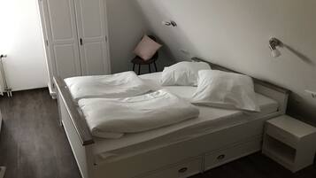 Ein Schlafzimmer mit einem Bett, einem Nachttisch, einem Sessel und einem Kleiderschrank.