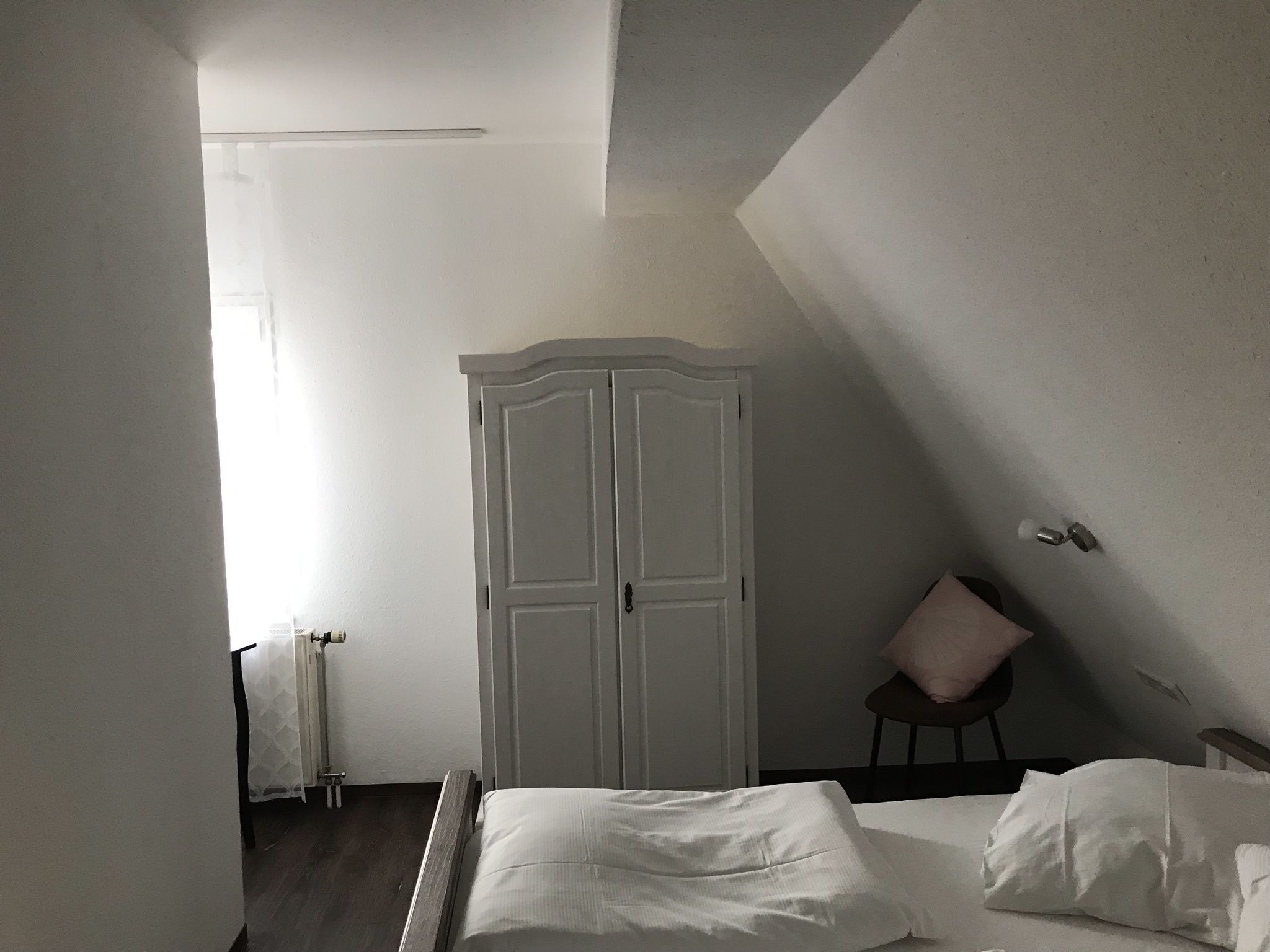 Ein Schlafzimmer mit einem Bett, einem Kleiderschrank und einem Sessel.