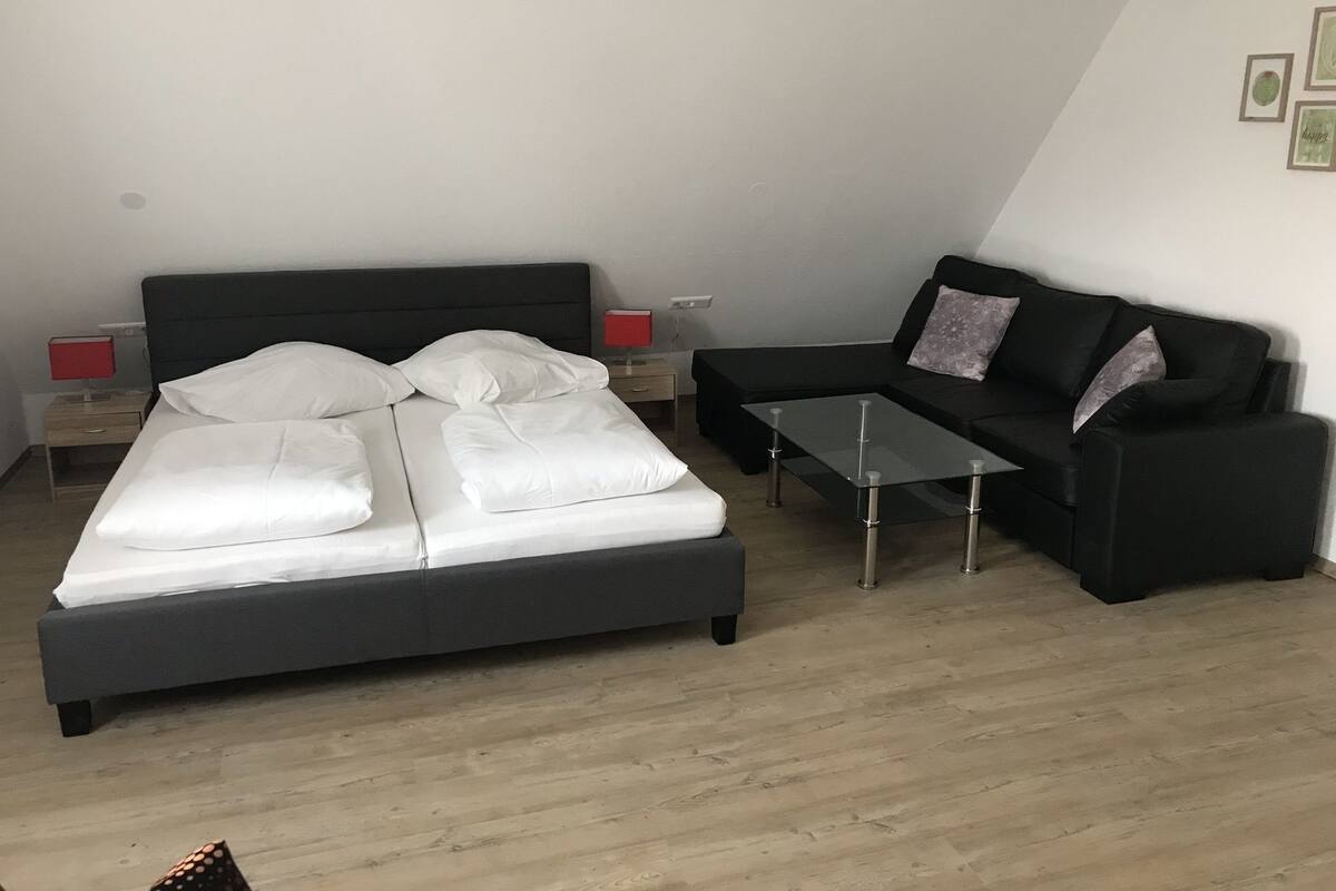 A bedroom with a bed, a sofa, a coffee table, and bedside lamps.