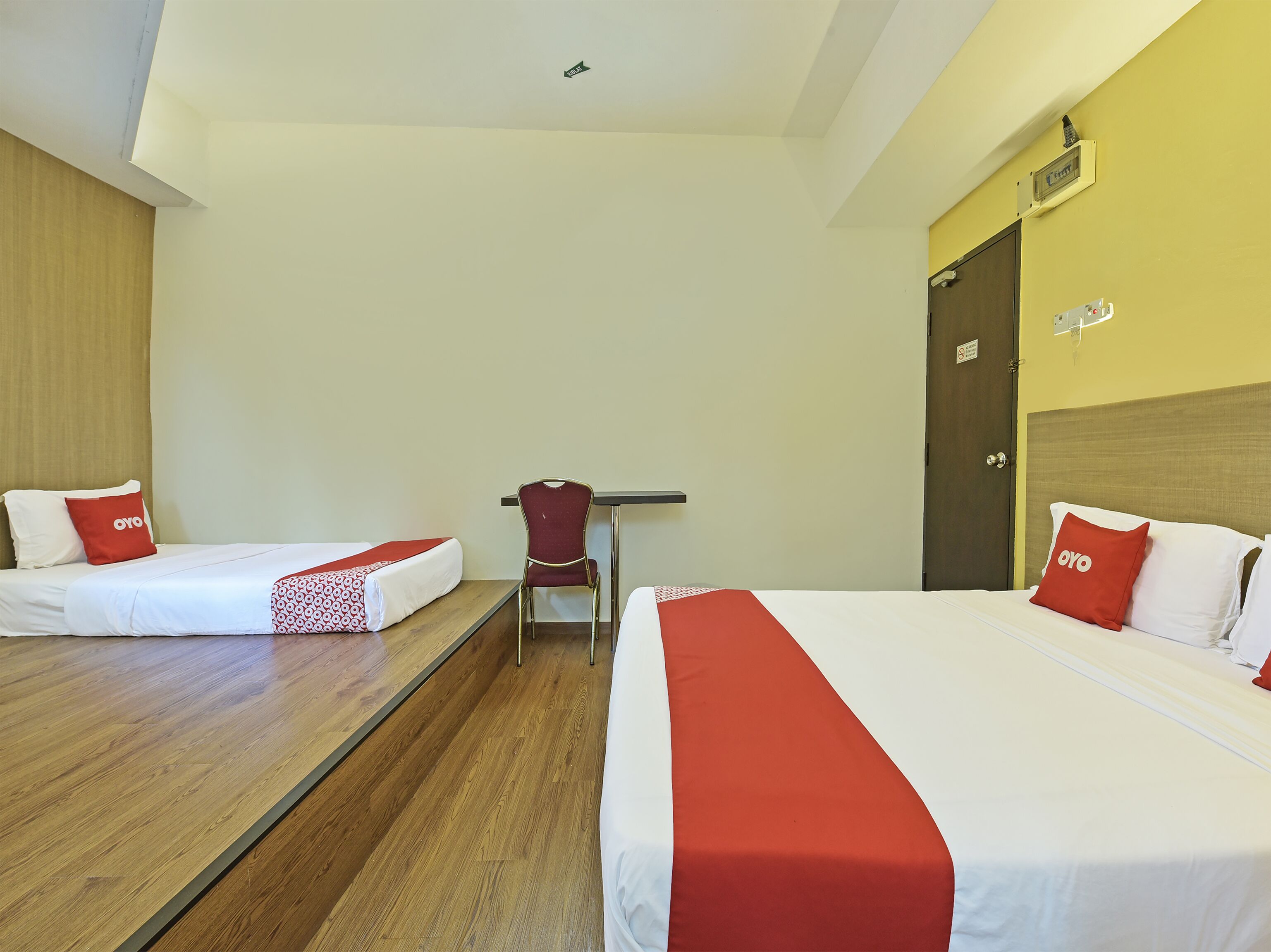 A hotel room with two beds, a desk, and a chair.