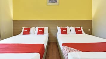 Een hotelkamer met twee bedden, elk met witte lakens en rode kussens, en een ingelijst kunstwerk aan de muur.