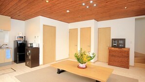 Una cocina moderna con microondas, refrigerador y armarios. Hay una mesa de comedor de madera con un florero.