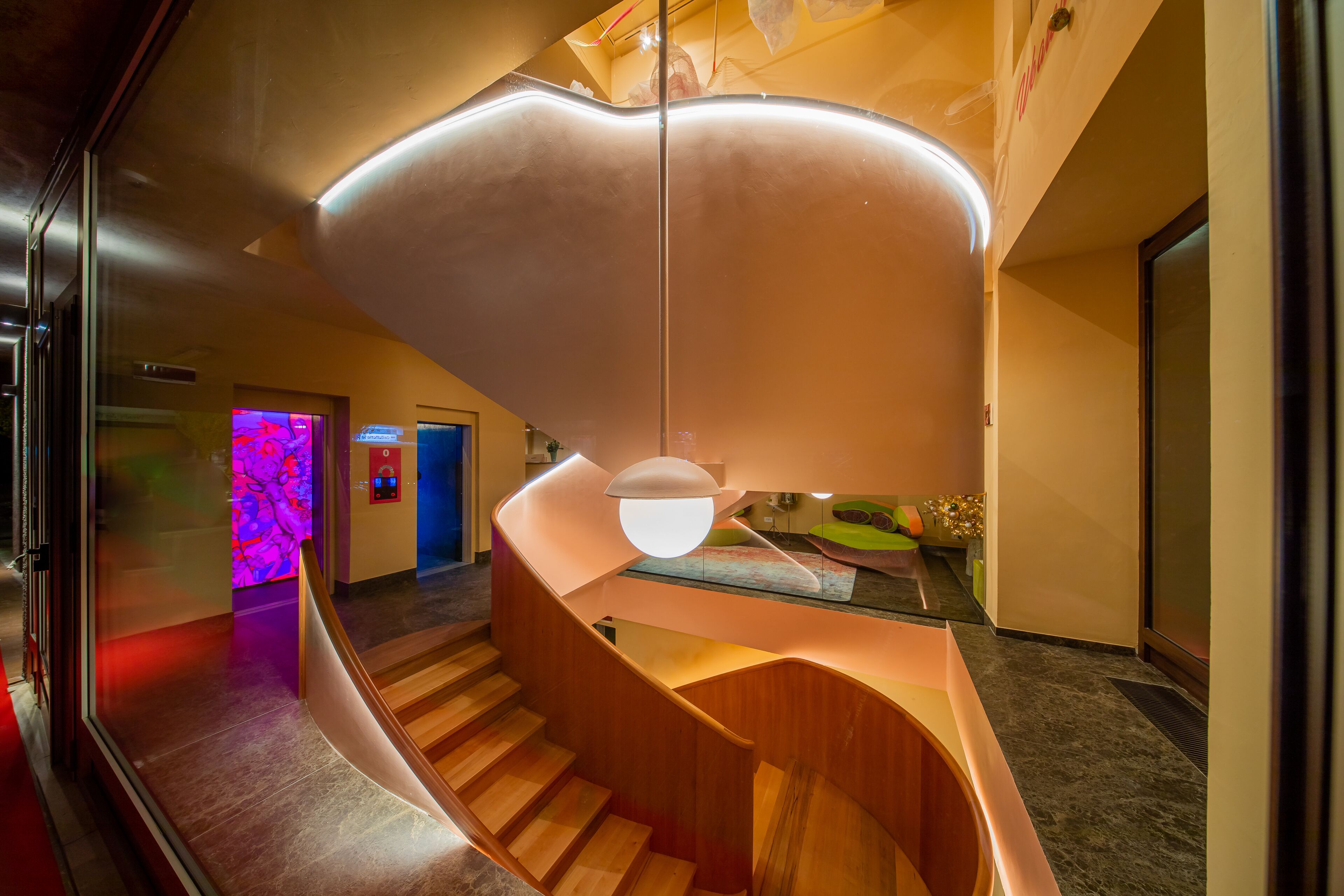A modern interior with a curved staircase, a glass railing, and a unique ceiling light fixture.
