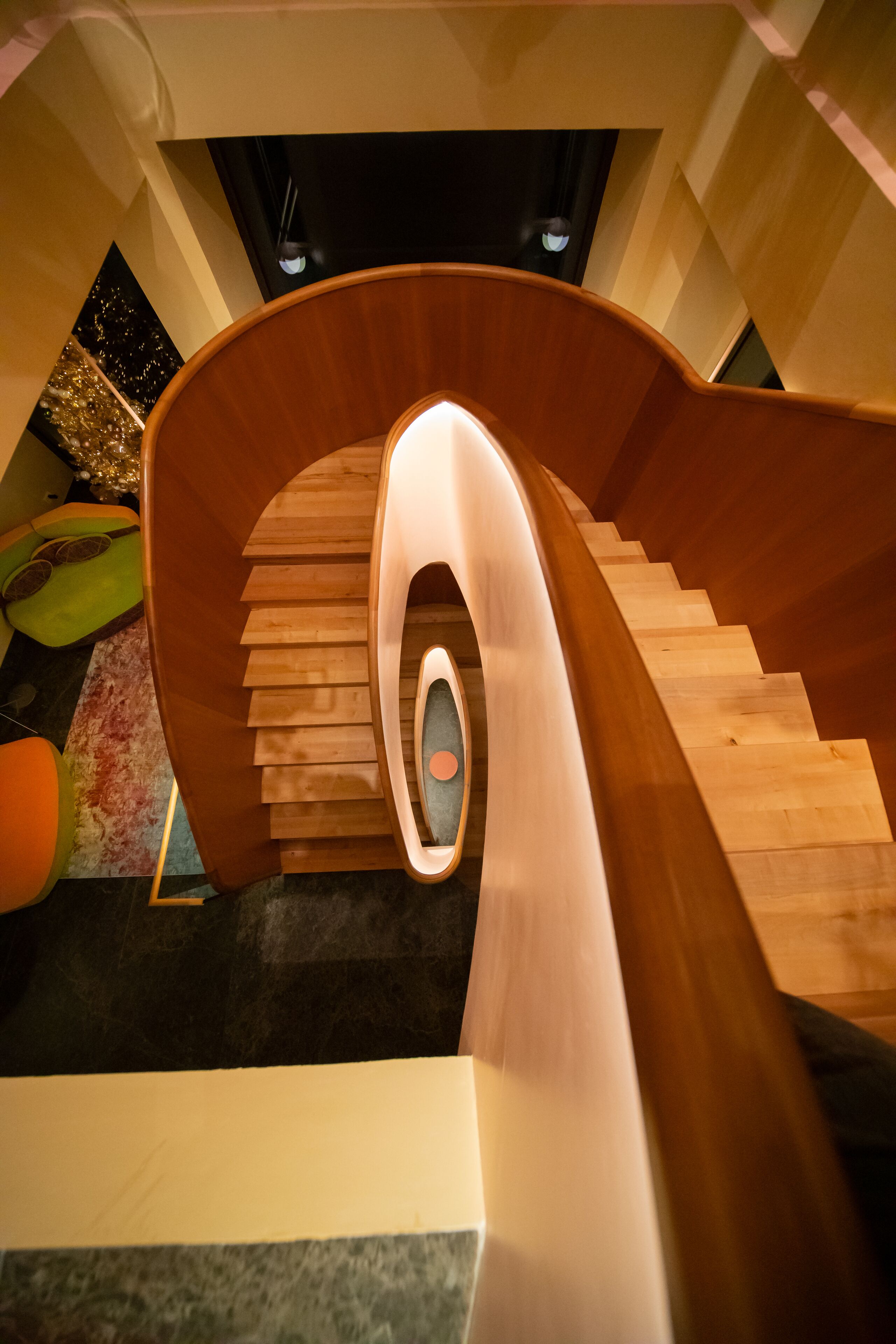 A spiral wooden staircase with a central light fixture.