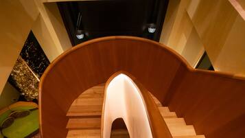 A spiral wooden staircase with a central light fixture.