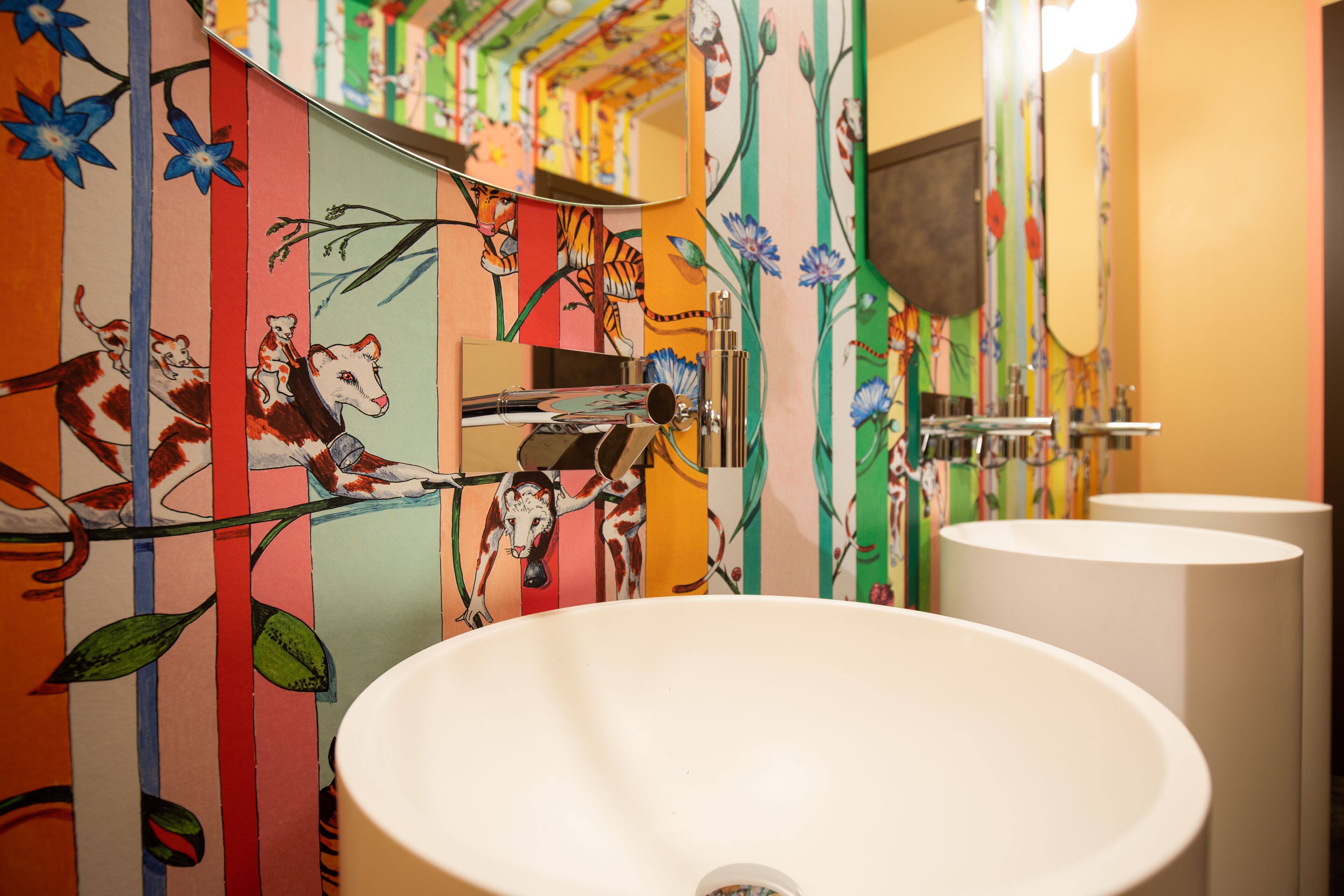 A bathroom with colorful striped walls, a white sink, and a mirror.