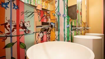 A bathroom with colorful striped walls, a white sink, and a mirror.