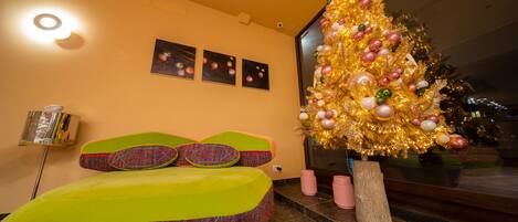 A modern room with a colorful bed, a large Christmas tree, and three framed pictures on the wall.