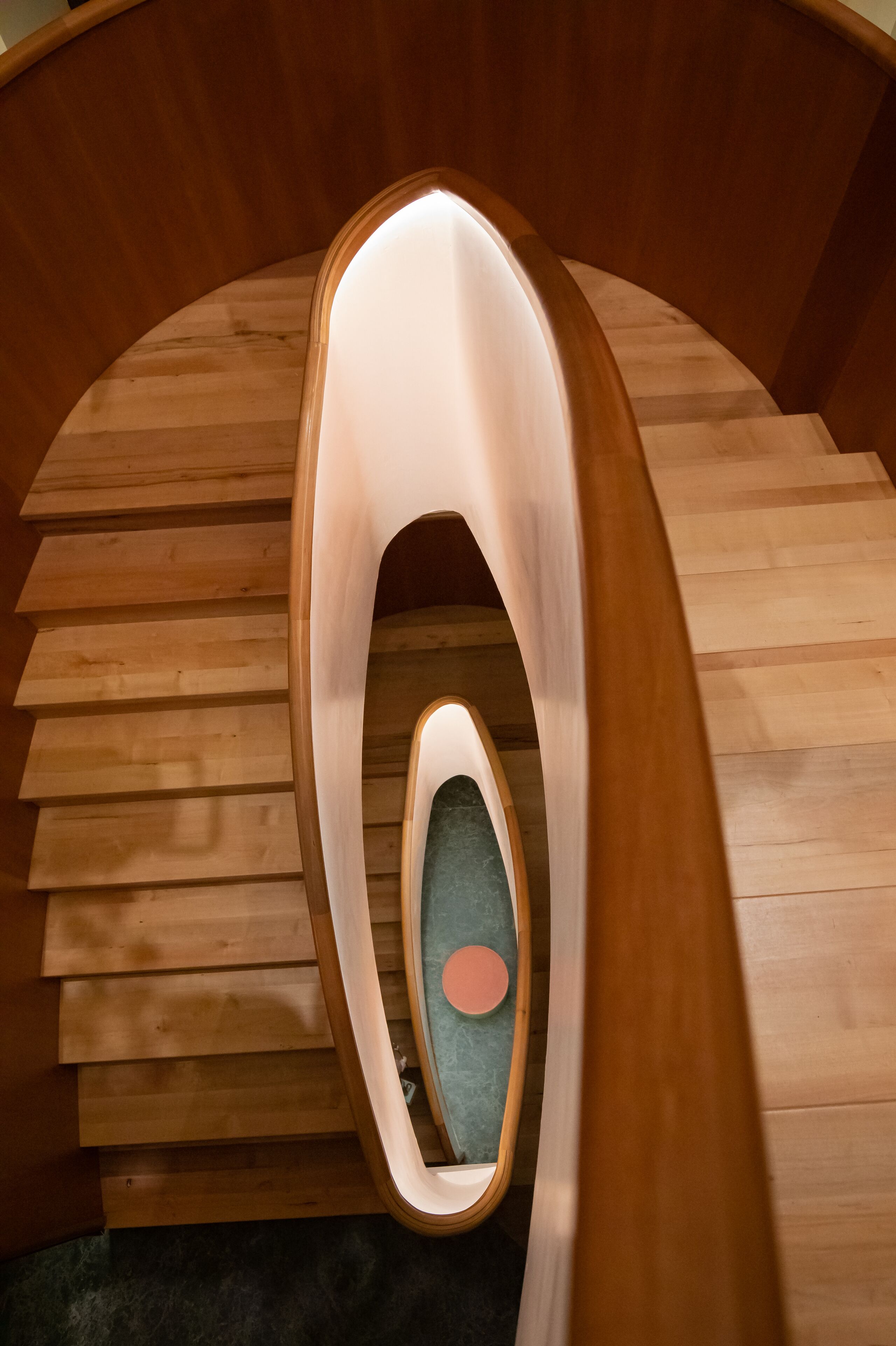 Un escalier en colimaçon avec des marches en bois et un luminaire central.