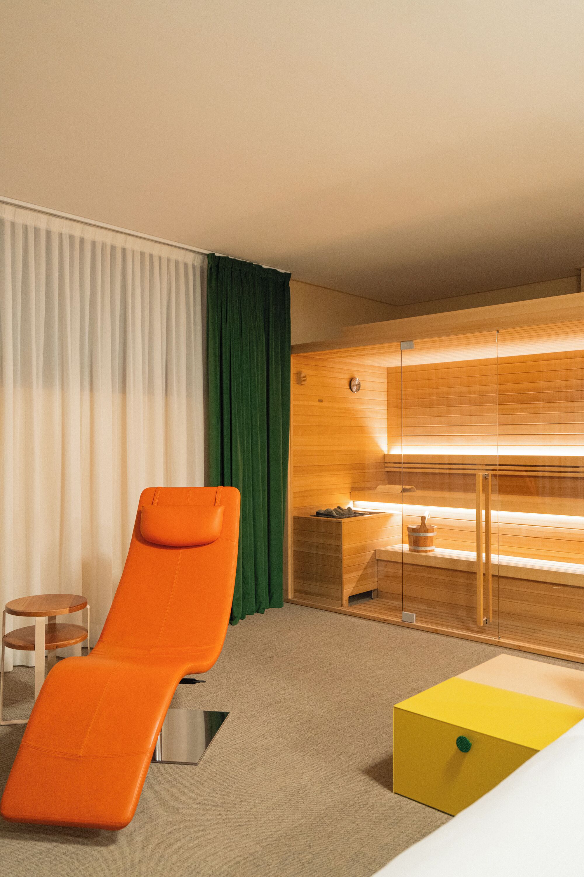 Ein modernes Zimmer mit einer Holzauszeit, einem gelben Pouf und einer hölzernen Sitzbank.