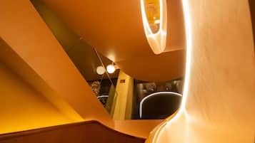 Una escalera de caracol con un aplique circular en la parte superior, escalones de madera y un diseño de interiores moderno.