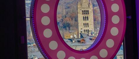 A window with a circular mirror and a view of a mountain and a tower.