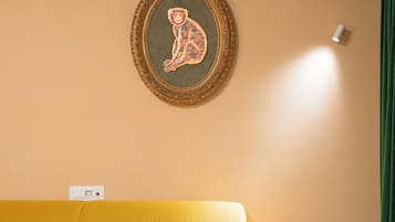 A room with a yellow sofa, a framed artwork on the wall, and a green curtain.