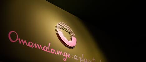 A sign with the text "Omamallounge: a place to share" and a stylized logo.