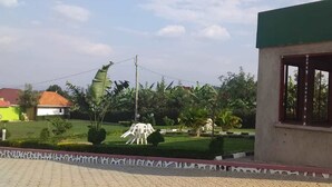 Un edificio con fachada verde y un logotipo, rodeado de un jardín bien cuidado con una estatua y un pequeño estanque.