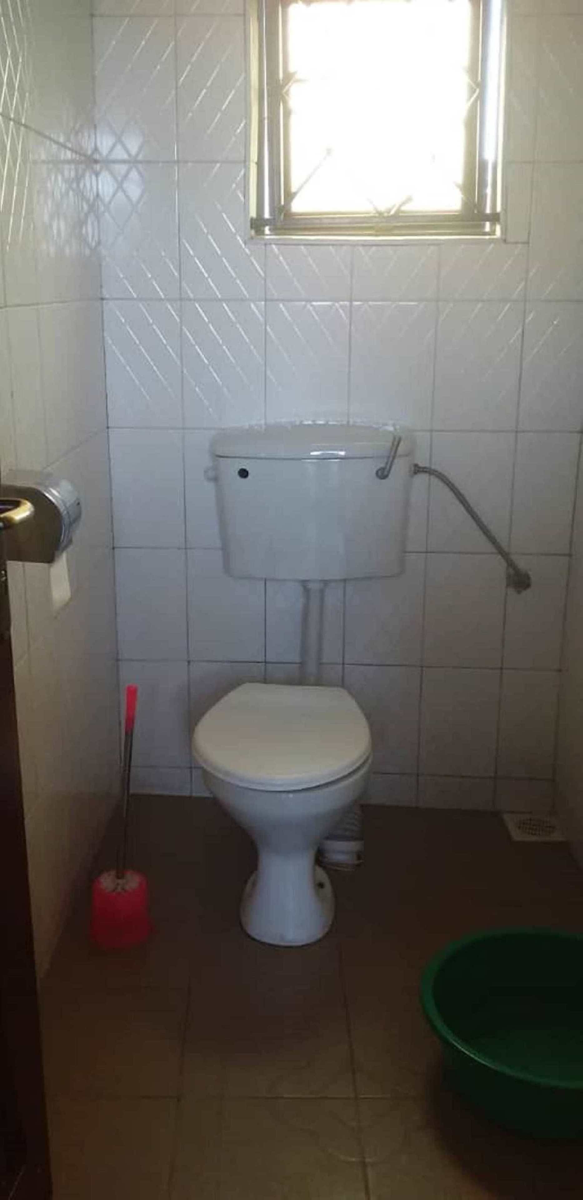 Une petite salle de bain avec des toilettes, une fenêtre et un lavabo vert.