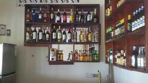 Una cocina con un refrigerador y estantes llenos de botellas y recipientes varios.