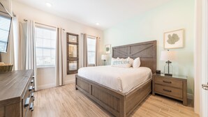 A bedroom with a wooden bed, a nightstand, a dresser, and a window with curtains.