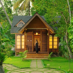 A wooden house with a porch, surrounded by lush greenery. - Cyrus Resort by Tolins Hotels & Resorts (Cherthala)