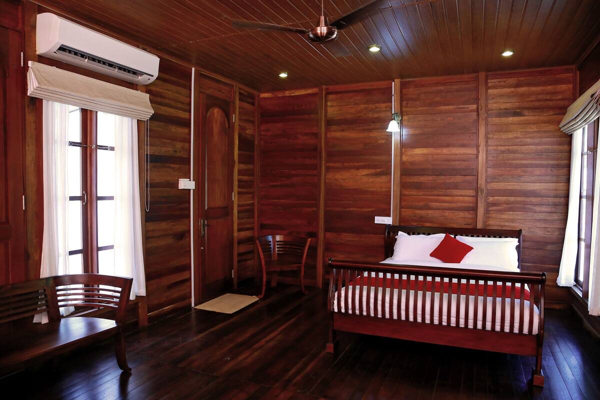Ein Zimmer mit Holzwänden, einem Bett, einem Sessel und einer Klimaanlage.