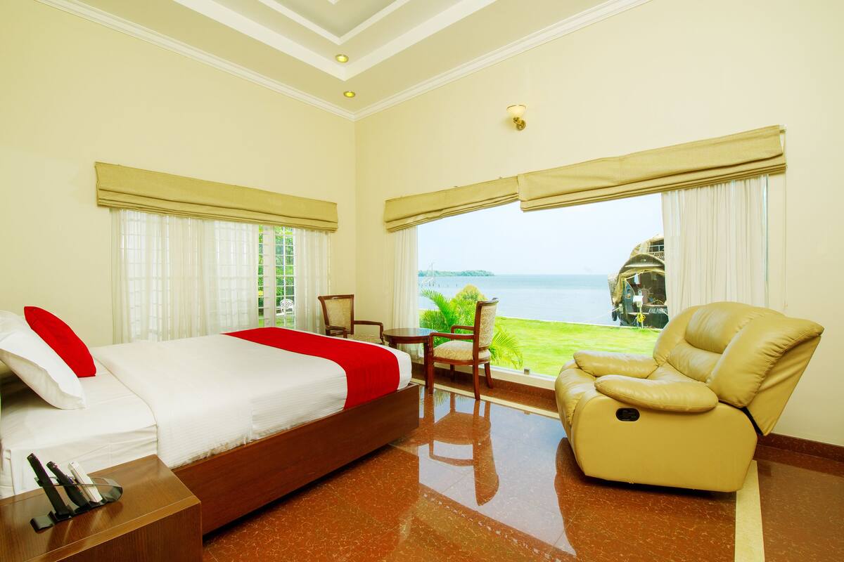 Ein Hotelzimmer mit Bett, Stuhl, Tisch und Meerblick.