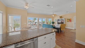 A spacious kitchen with granite countertops, a dining area with chairs, a ceiling fan, and a view of the outdoors. - 102 6th St S-downstairs 3 Bedroom Home (Bradenton Beach)