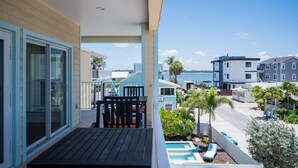 A balcony with a pool, a view of the sea, and a building with a flag. - 102 6th St S-downstairs 3 Bedroom Home (Bradenton Beach)