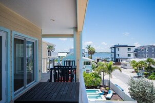 Un balcón con piscina, vista al mar y un edificio con una bandera.