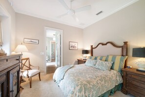 A bedroom with a bed, a chair, a dresser, a nightstand, a lamp, a ceiling fan, and a door leading to another room. - Dockside Darling 3 Bedroom Home by RedAwning (Bradenton Beach)