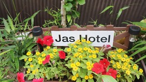 Cartell de 'Jas Hotel' envoltat de flors colorides.