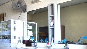 Une salle de bain avec deux lavabos, un miroir, un ventilateur et une étagère avec des serviettes.