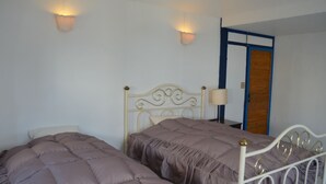 Une chambre avec deux lits, une porte en bois et des lampes fixées au mur.