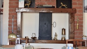 A dining area with a brick wall, a fireplace, and a framed painting above it. - Bewdley Hill House (Kidderminster)